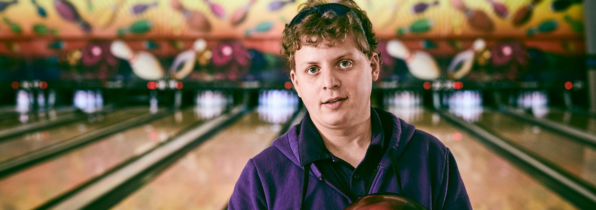 Aaron, living with LGS, in front of a bowling alley.